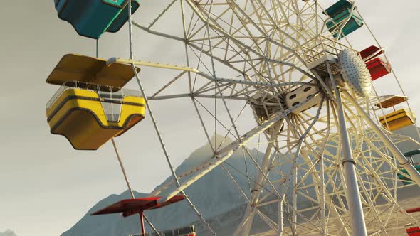 Colorful Ferris wheel spinning slowly in a mountain landscape in endless loop.