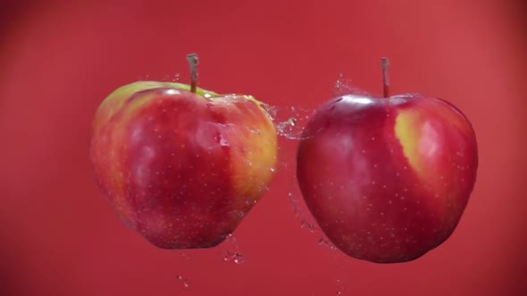 Two Red Apples Are Flying Towards Each Other, Colliding on the Red Background