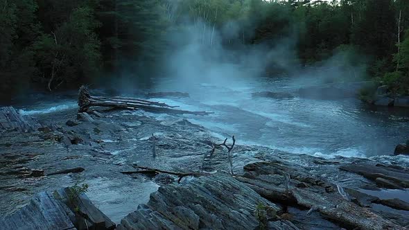 Aerial drone shot flying in slow motion over the dark wet rocks and misty waterfall at Big Wilson Fa