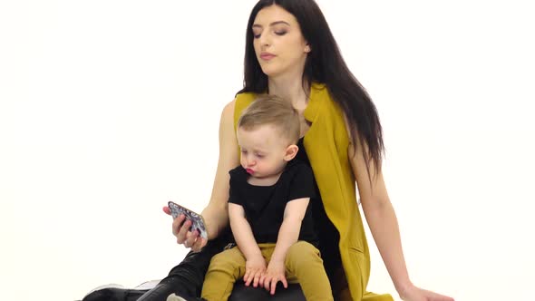 Girl Tells and Shows Something on the Smartphone To Her Child, White Background