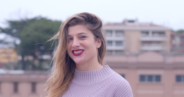 confidence, youth - young carefree woman on the roof smiles at the camera