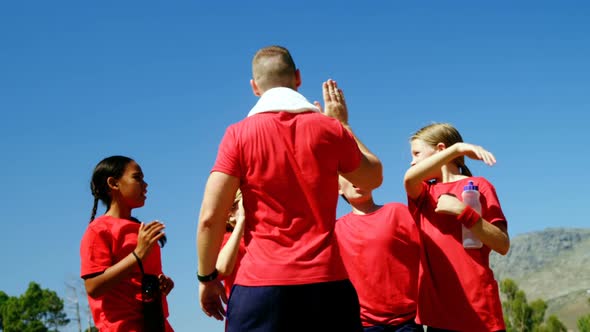 Trainer and kids giving high five to each other in park