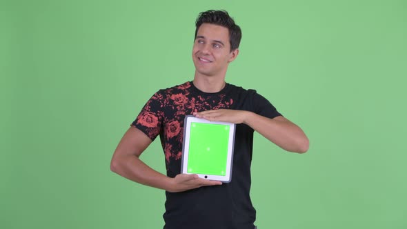 Happy Young Handsome Man Thinking While Showing Digital Tablet