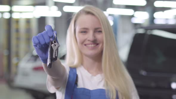 Close-up of Beautiful Blond Caucasian Woman Showing Car Keys To Camera. Young Cheerful Auto Mechanic