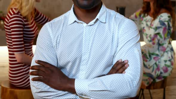 Man smiling at camera and friends interacting in background 