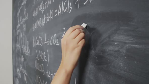 Hand of Scientist Writing Equations on Chalkboard