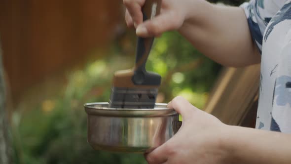 Female Hand Holds a Brush and Stirs Black Paint