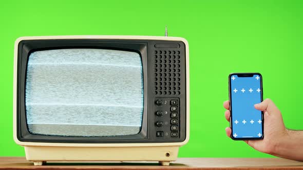 Old Television with Grey Interference Screen on Green Background and Smartphone with Blue Chroma Key