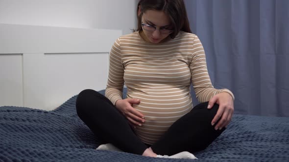 Young Pregnant Woman with Glasses Stroking Her Belly