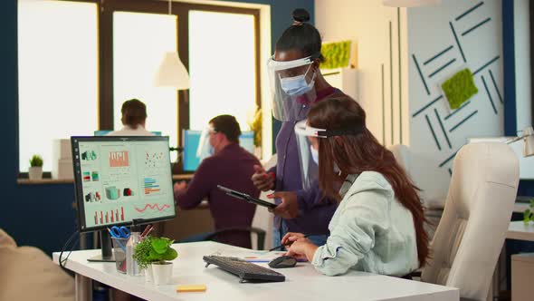 Multiethnic Coworkers with Protection Masks Checking Annual Statistics