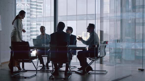 Office concept: young people cheering a mature businesswoman sitting at desk