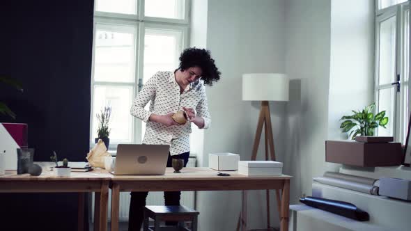 Young online shop owner packing box with items ordered by client