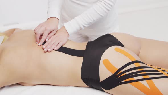 Therapist is applying kinesio tape to female body. Physiotherapy, kinesiology and recovery.