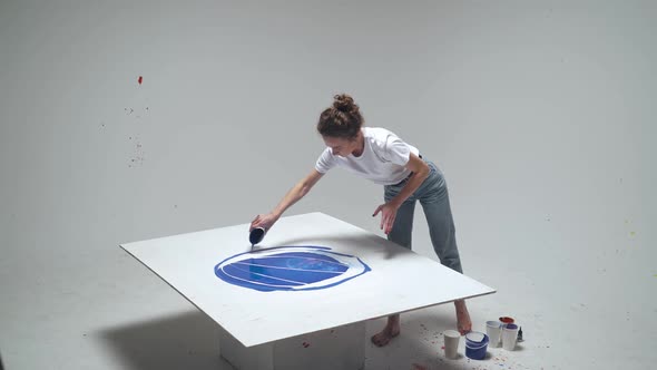 Young Female Artist Draws By Pouring Paint on the Canvas a Talented Artist Draws a Color Blue