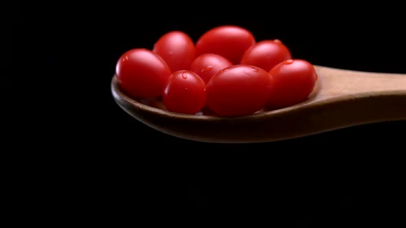 Slo-motion cherry tomatoes falling off wooden spoon