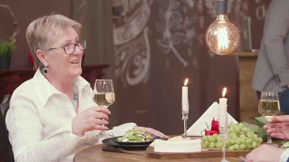 Senior Woman Clinks a Glass of Wine with Her Husband