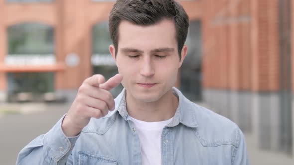 Young Man Pointing with Finger Outdoor