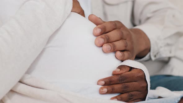 Closeup Male and Female Hands Stroking Pregnant Belly of Woman in White Clothes African American