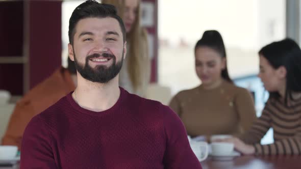 Portrait of Confident Handsome Caucasian Man with Black Hair and Beard Looking at Camera and Smiling