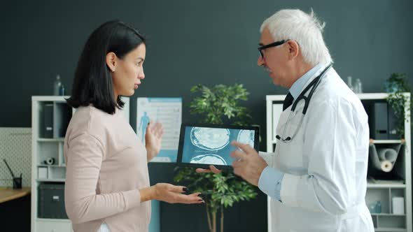 Doctor and Patient Discussing Health Looking at Mri Images on Tablet Screen in Office
