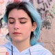 Blue haired teenage girl in oversize hoodie drinking coffee to go against graffiti wall - VideoHive Item for Sale
