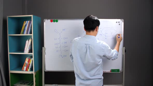 Asian Teacher Writing Scientific Formula On The Whiteboard