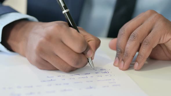Hands of African Businessman Writing on Paper Close Up
