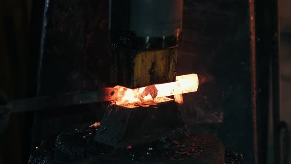 Man Blacksmith Forging Piece of Hot Iron Under Hydraulic Press at Workshop of Forge Factory. Slow