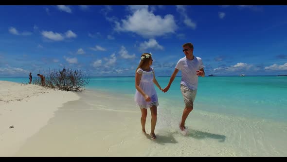 Boy and girl sunbathing on paradise coast beach break by transparent water with bright sand backgrou