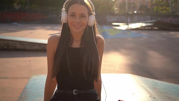 Young woman at skate park listening to music