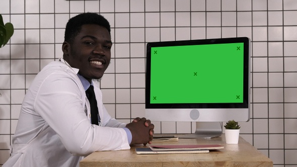Black doctor talking to camera sitting next to computer
