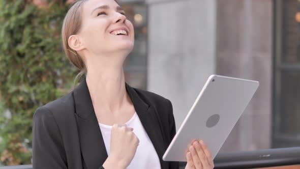 Young Businesswoman  Sitting Outdoor and Cheering Success on Tablet