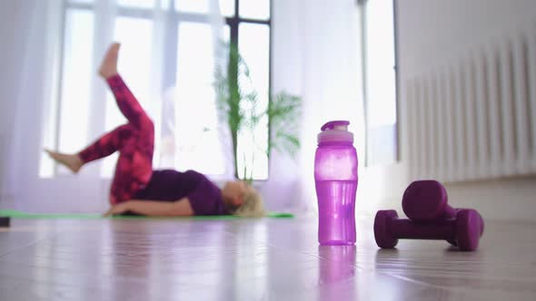 Fitness Training Overweight Woman Lying on Her Back and Doing Exercise for Her Legs Bottle and