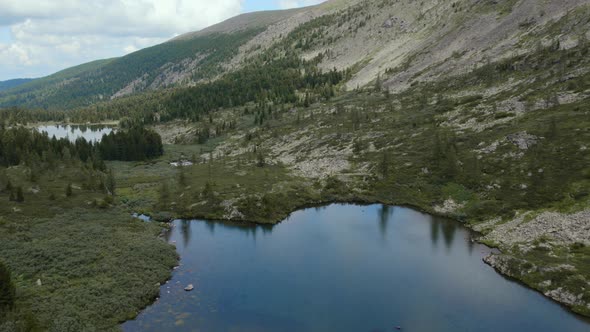 Karakol lakes and green forest under blue sky with white clouds