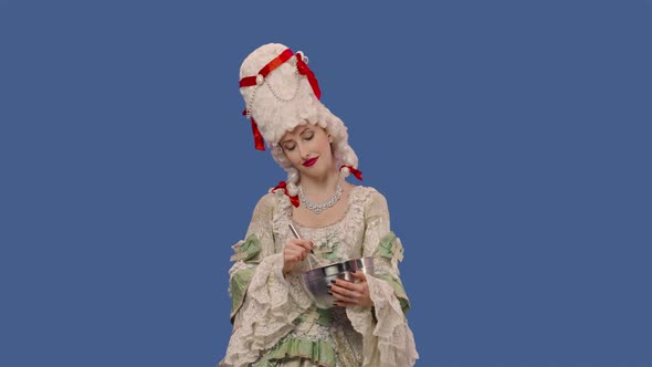 Portrait of Courtier Lady in Vintage Lace Dress and Wig is Preparing Food Whisking Something in a