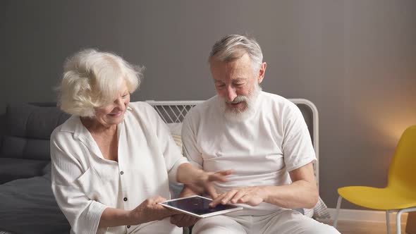 Happy Elderly Caucasian Man and Woman Play Online Games Look at Screen