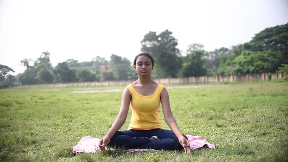 Teenage young Asian Indian girl doing meditation and Indian yoga pranayam at morning sunrise