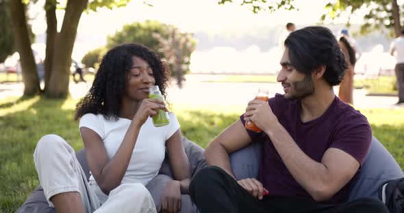 Multi Cultural Couple Drinking Juice in Park