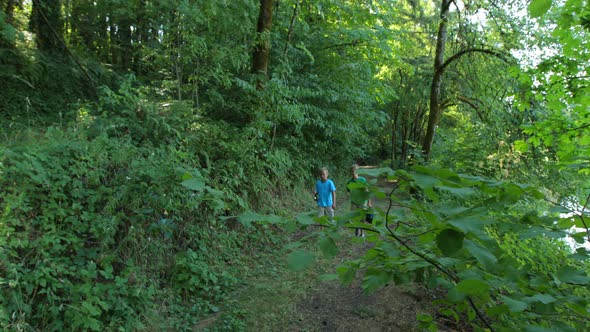 Two boys walking through woods with fishing gear