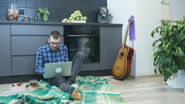 Motivated young man in glasses working on laptop computer from home, finding new ideas