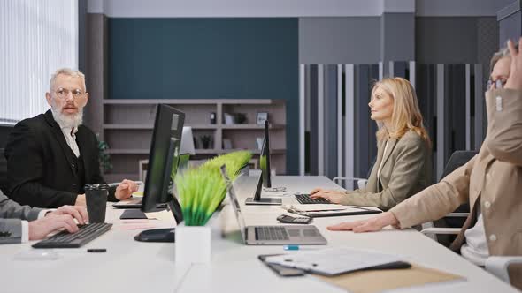 Tracking Shot of Elderly Coworkers Group Sitting at Modern Workplace Typing on Computers and