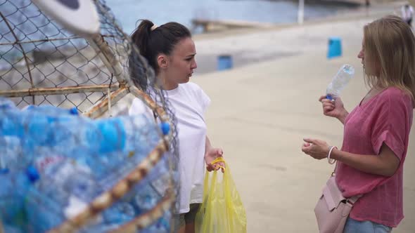 Confident Young Women Talking Putting Empty Plastic Bottles in Special Place on the Beach