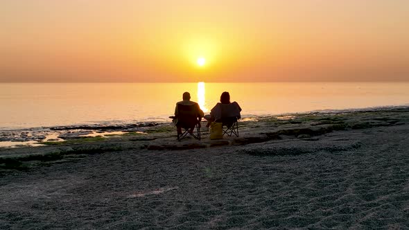 People Sit on the Beach and Watch the Sunset