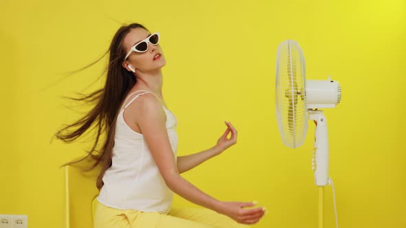 Sexy Woman With Long Hair Is Posing In Front of Electric Fan