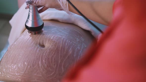 Large Woman Client with Gel on Belly Undergoes Vibromassage