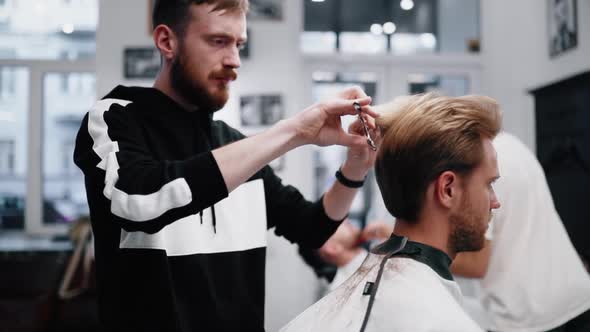 Barber Performs a Haircut with Scissors. New Fashion of Haircuts