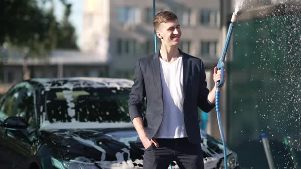 Portrait of Confident Successful Positive Man Posing with High Pressure Water Jet in Slow Motion at