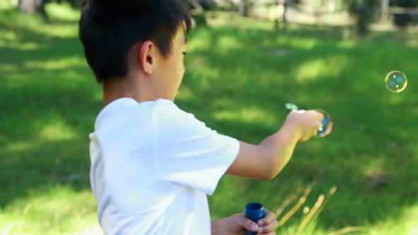 Boy blowing bubbles in park