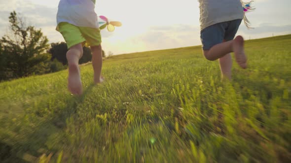 Unknown Girl and Boy Running on Green Meadow at Sunrise Time