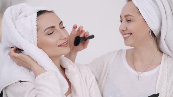 Two Beautiful Women with Wrapped Hair in Towels Are Doing Make-up